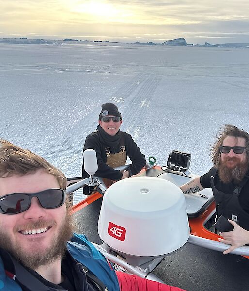 Three dudes in a quad bike on the ice looking very happy