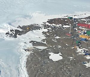 An aerial view of many multi coloured buildings on an icy, rocky, landscape.