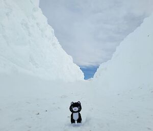 A stuffed cat toy on the snow looking down to the wharf