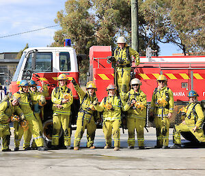 10 people in fire fighting uniforms stand infront of a red fire truck