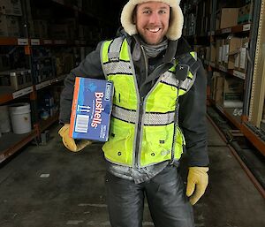 An Antarctic expeditioner carrying a box of Bushells tea from the supply store