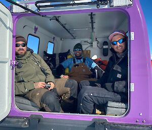 Three expeditioners sitting in the back of an Antarctic Hagglunds vehicle