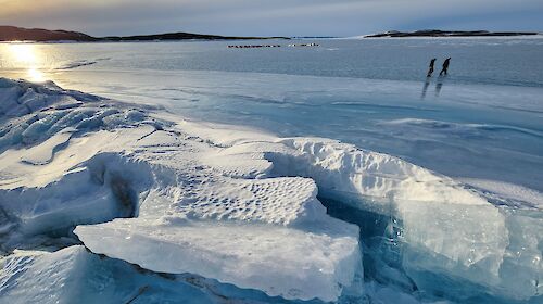 Blocks of ice in the foreground, two people in the background