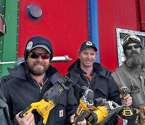 A man rendered in black and white holding a hand saw and drill is with three men