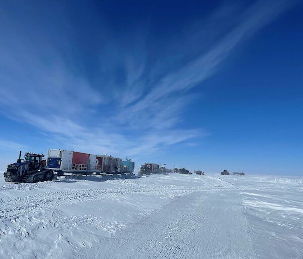 A tractor and a convoy of vehicles traveling across the ice