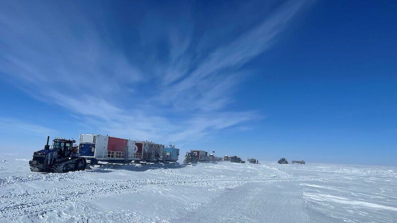 A tractor and a convoy of vehicles traveling across the ice