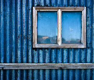 A blue rusty corrugated iron shed with a window