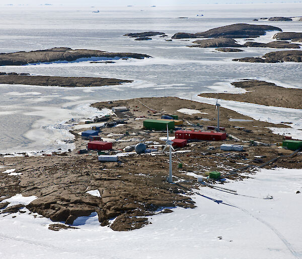 Aerial view of a cluster of buildings on a rocky outcrop surrounded by ice