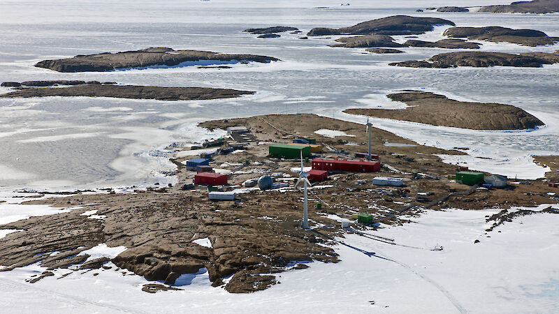 Aerial view of a cluster of buildings on a rocky outcrop surrounded by ice