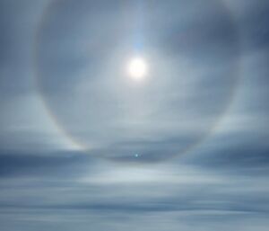 Halo around the sun created by light refracting through ice particles in the atmosphere