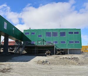 A big green building with a small yellow building to the right.