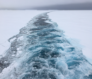 A channel of water is carved through ice behind the icebreaker Nuyina.