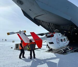 BK117 helicopter being unloaded via the rear ramp of a C-17 Globemaster aircraft.