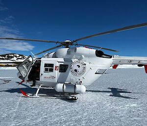 White BK117 Helicopter parked on snow preparing for departure