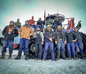 Expeditioners standing on and in front of a tractor parked on snow