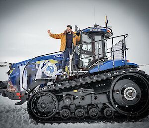 Expeditioner waving from a tractor parked on snow prior to departure