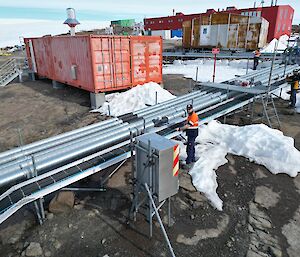 Three people are laying fibre optic cable into metal cable trays that are built above a rocky landscape