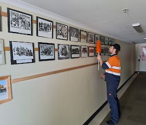 A man in high vis dusting a row of photographs