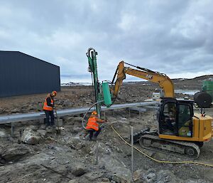 Two men in high vis help a man using a digger