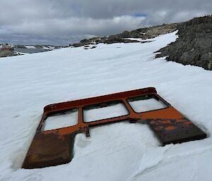 Tractor cab buried in snow with the RSV Nuyina at harbour in the background