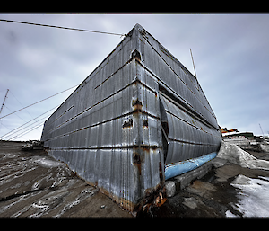 Corrugated iron airplane hangar under a grey cloudy sky