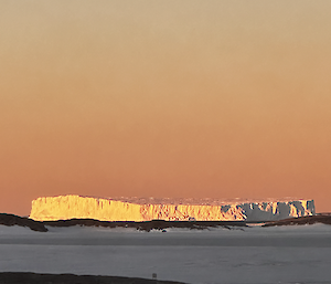 Sun glowing off a large iceberg behind Bechervaise island