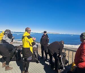 Pre-departure briefing on the deck with walkers standing in the sun with packs on
