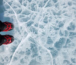 Boots with ice spikes standing on cracked ice