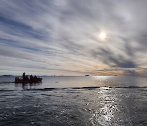 Expeditioners in an IRB boat cruise along the water near Casey station