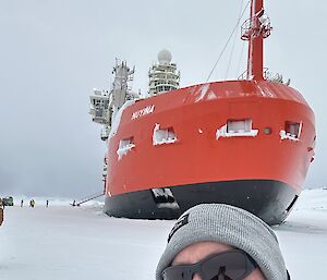 Shane standing in front of the Nuyina on sea ice