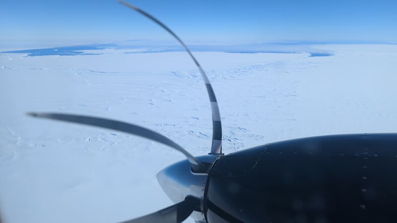View of snow and ice over an aircraft propeller.