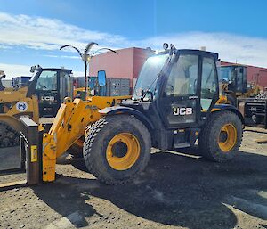 4 large off road wheeled forklift with enclosed cab pictured with various other plant vehicles with field store building in background.