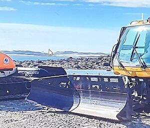 two wide tracked dozer blade equipped snow plough vehilcles with wide enclosed cabs one orange one yellow.