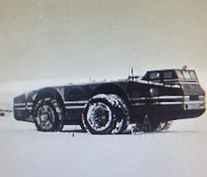 Black and white photo of a large long vehicle with a raised dual cab side on. Prominent 3m high tyres with with dual stacked tyres on front axle.