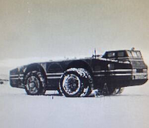 Black and white photo of a large long vehicle with a raised dual cab side on. Prominent 3m high tyres with with dual stacked tyres on front axle.
