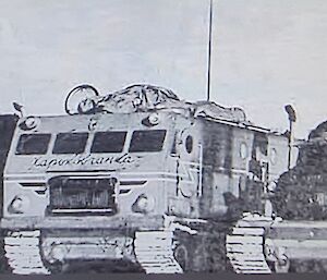 Black and white photo of three tracked vehicles from the front with lone figure in left foreground. All vehicles have extensive external  stowage and comms masts.