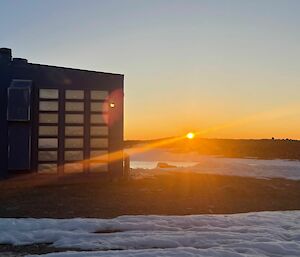 The sun setting below the distance escarpment, vibrant oranges with blue sky.