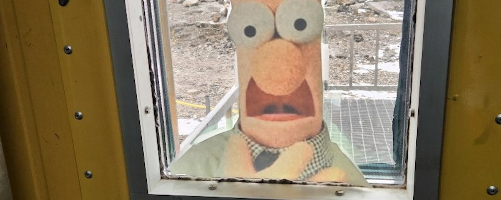 port view within a door with beaker from the Muppets taped to it