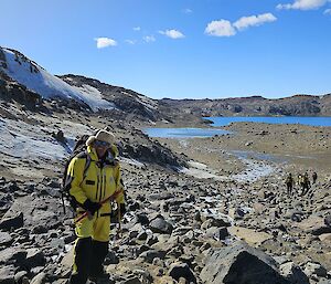 Expeditioner Scotty Lewis standing with ice pick in hand with the Vestfold Hills in the background