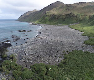 A barren hill in the distance with a rocky beach in the foreground.