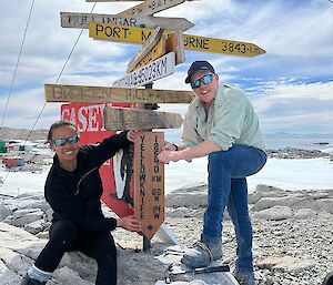 2 expeditioners smiling and holding sign that was newly installed on the casey signpost