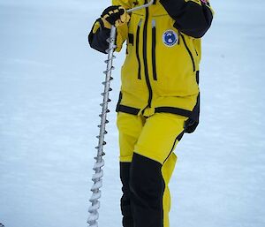 An expeditioner drilling into sea ice