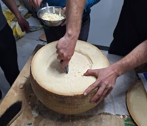 Cheese being scooped from the centre of the cheese wheel