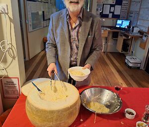 Doctor standing over the cheese wheel smiling