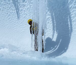 Fingers of ice hang down, with an expeditioner in the background.