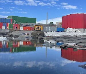 A pool of water in the foreground with Mawson's red green and blue buildings in the background.