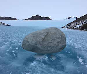 Rock balanced on what looks like frozen waves.