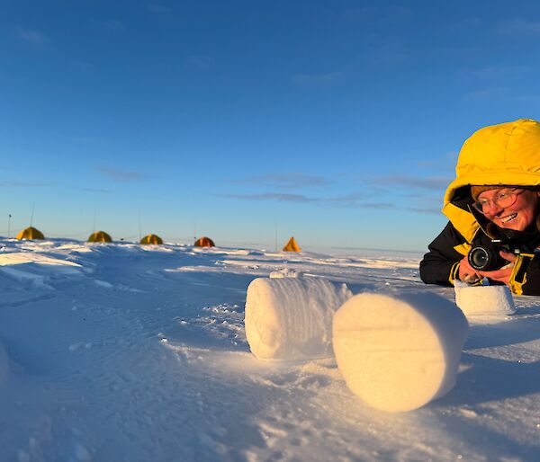 smiling expeditioner laying on snow admiring ice core samples