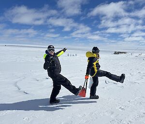 Two expeditioners walking across the snowy camp site