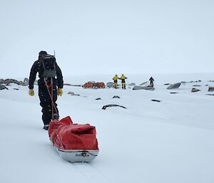 Expeditioner hauling a loaded sled across the snow
